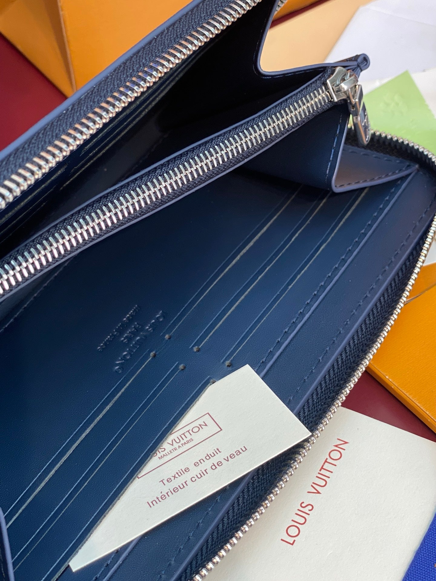 Louis Vuitton zip wallet interior showing debossed lining and silver hardware, dark blue.