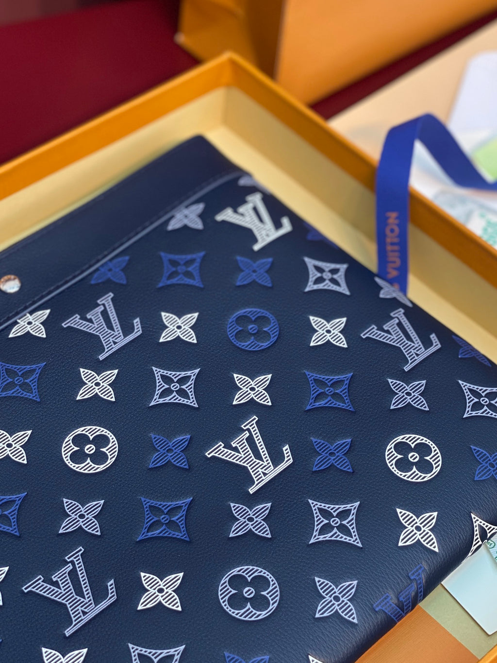 Blue Louis Vuitton small bag close-up of monogram pattern on front flap.