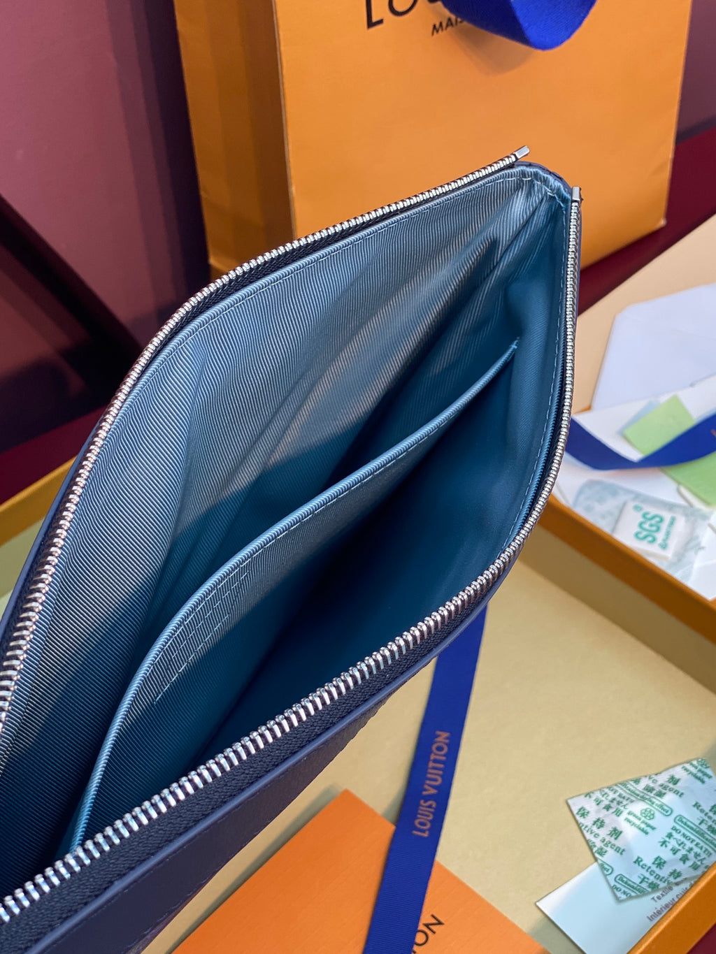 Blue Louis Vuitton small bag opened view with smooth interior and zipper track.