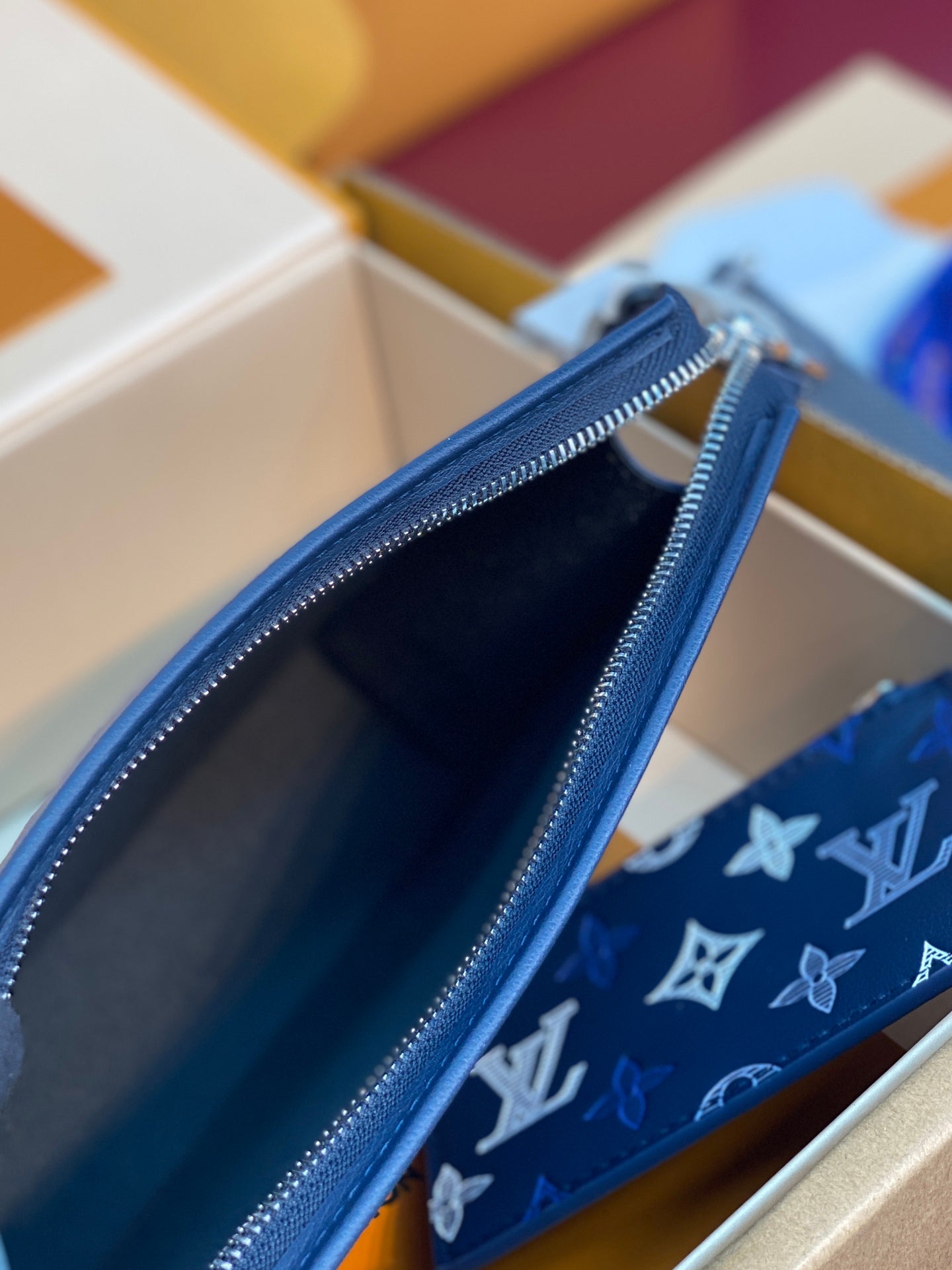 Open blue monogram pouch showing interior lining and top zipper