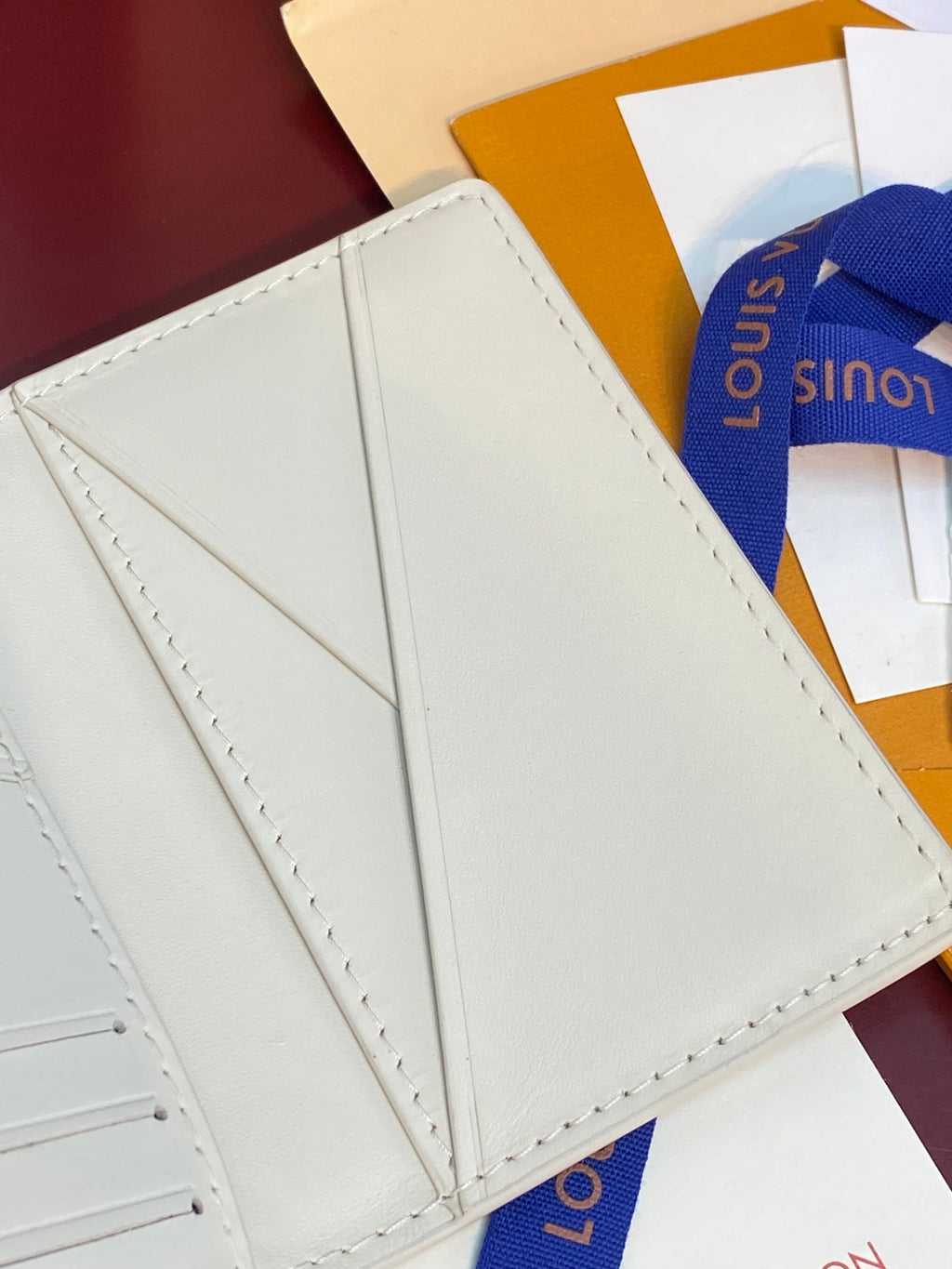 Men's Louis Vuitton small card wallet, interior panel close-up with stitched seams and center fold.