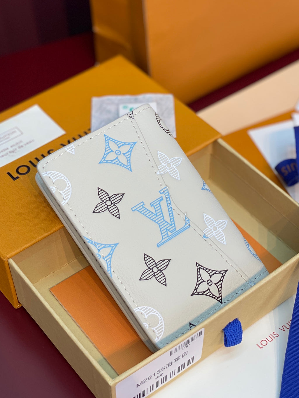 Men's Louis Vuitton small card wallet, white exterior with blue and black monogram motifs.
