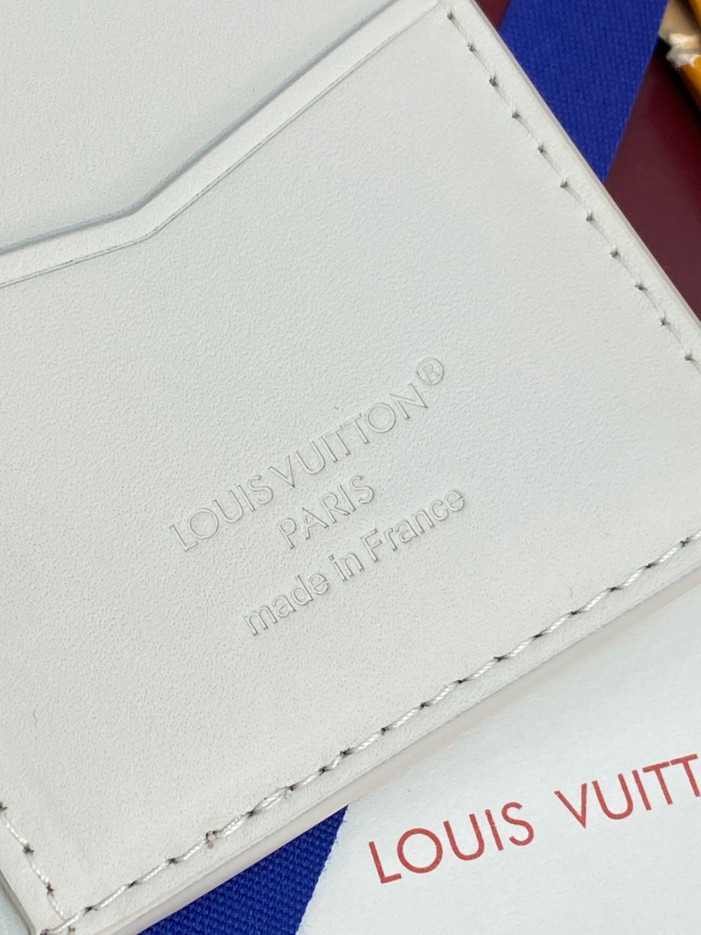 Louis Vuitton leather card holder corner, embossed branding and stitched trim