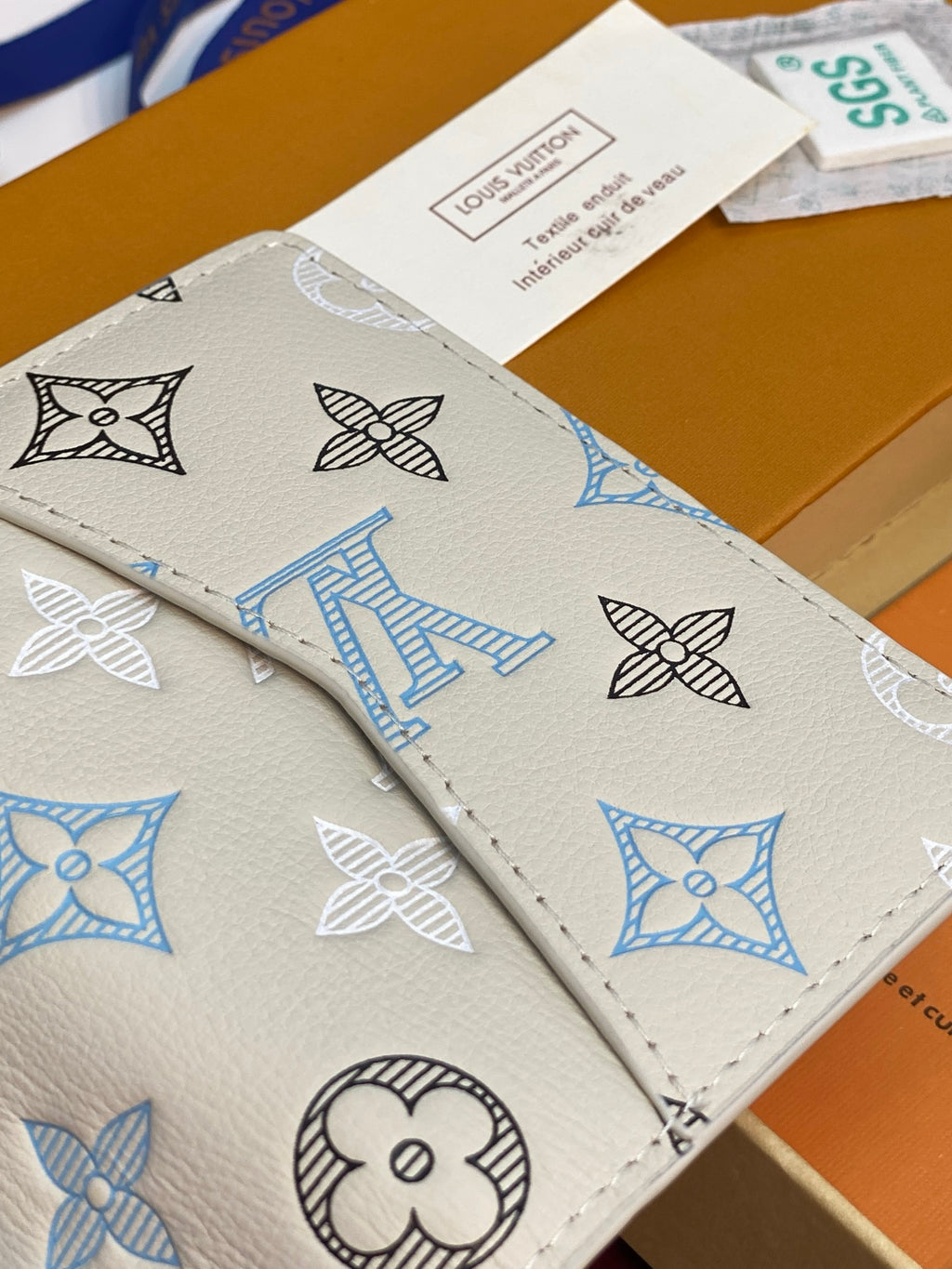 Men's Louis Vuitton small card wallet, close exterior with white, blue, and black monogram print.