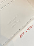 Louis Vuitton small bi-fold card holder, close-up of embossed brand text on white leather
