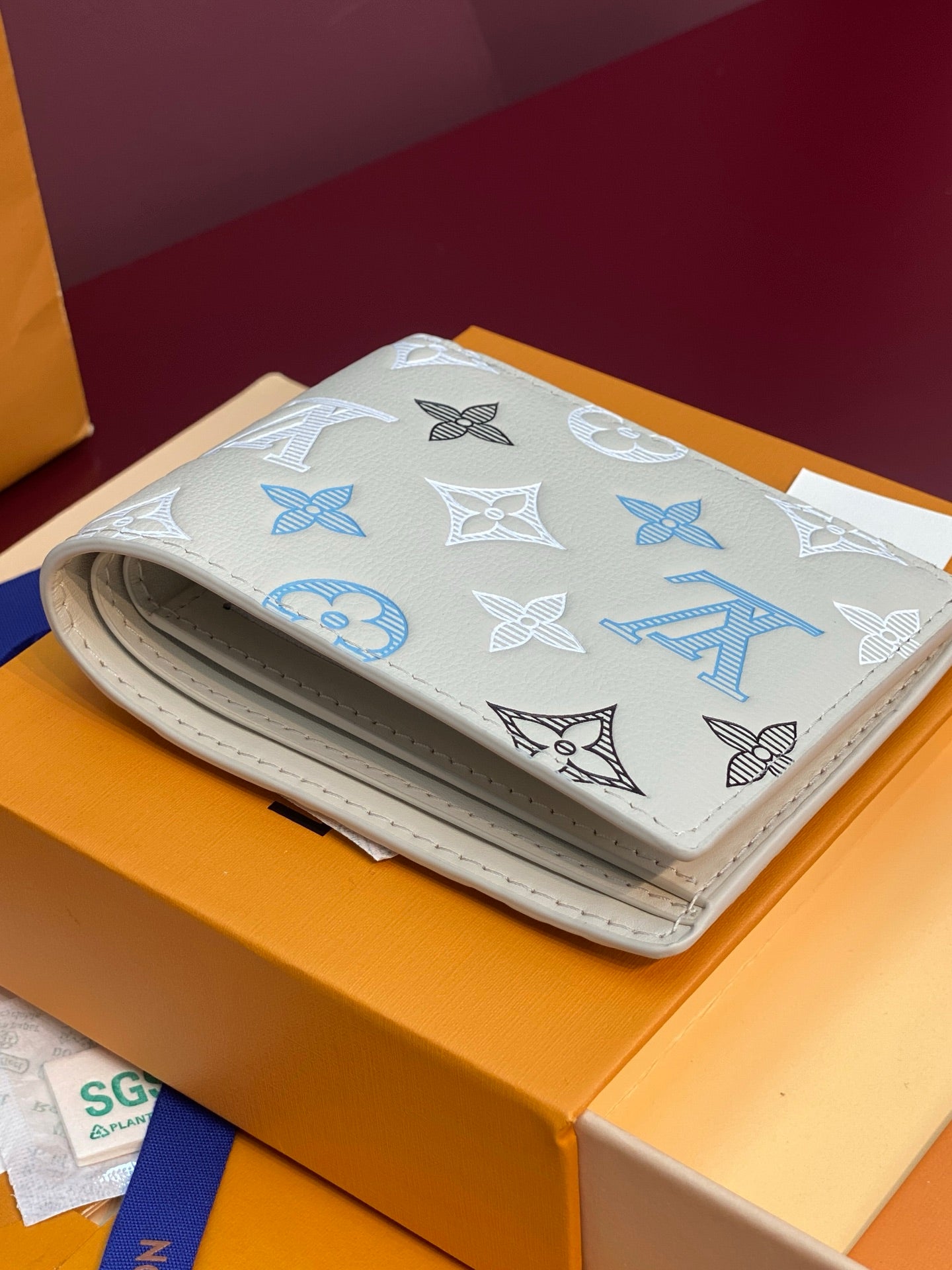 Louis Vuitton small bi-fold card holder, light blue monogram print with white fold-over flap