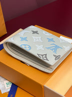 Louis Vuitton wallet folded, blue Monogram pattern on white exterior with stitched edge.