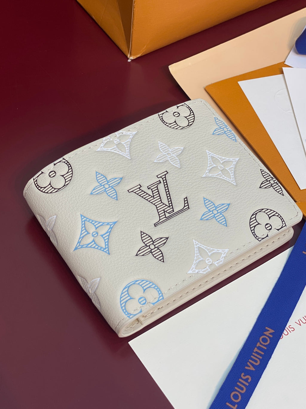 Louis Vuitton small bi-fold card holder, light blue monogram print on white leather