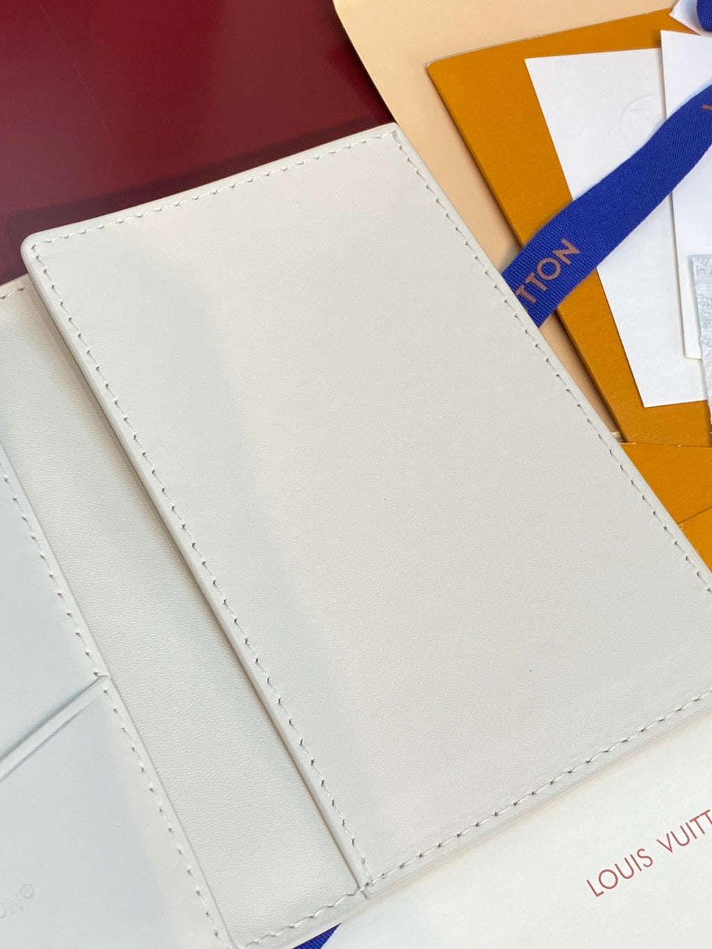 White bi-fold wallet outer panel with stitching along edges and flap.