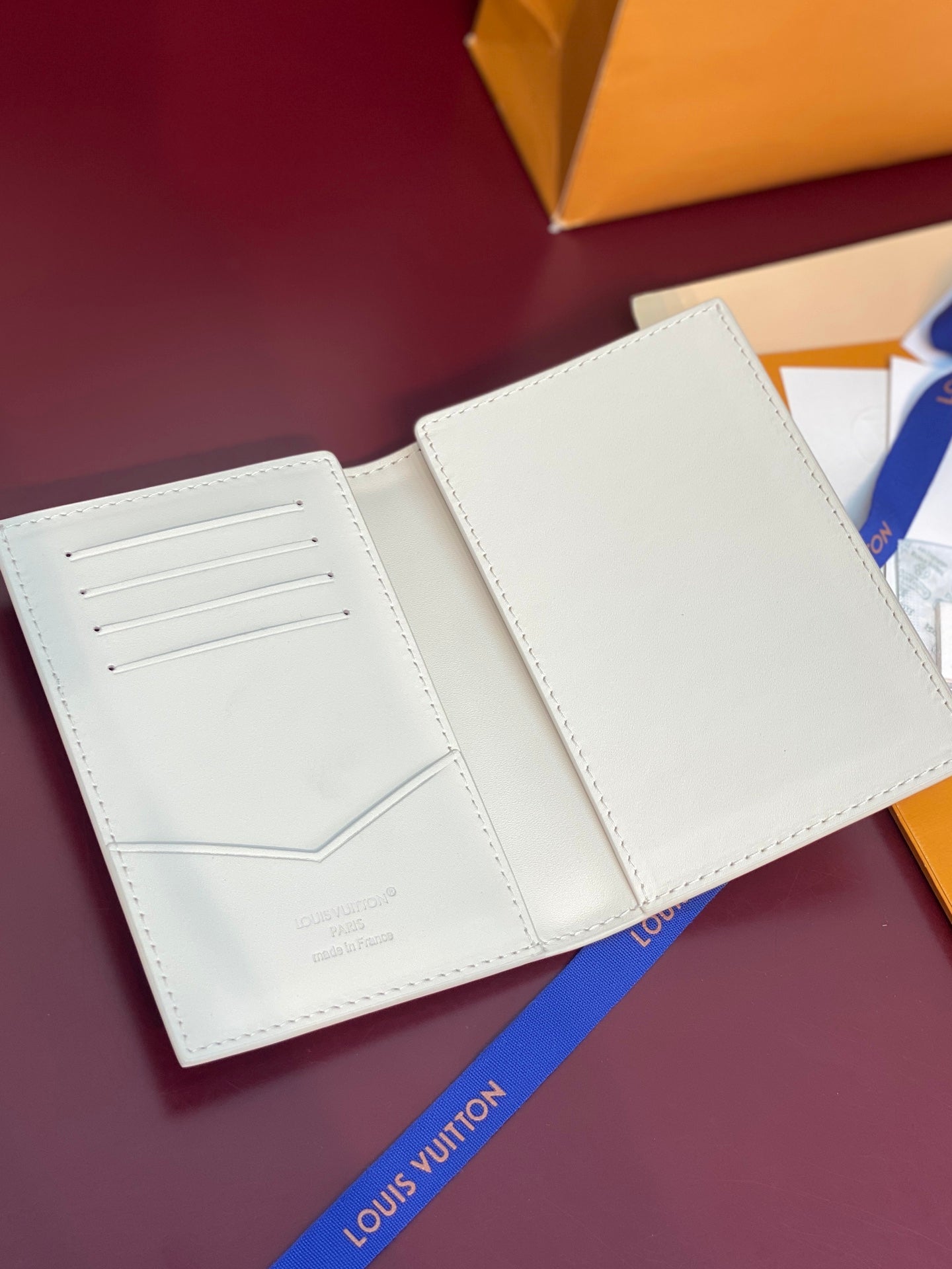 White bi-fold wallet open flat, showing two card-slot panels.