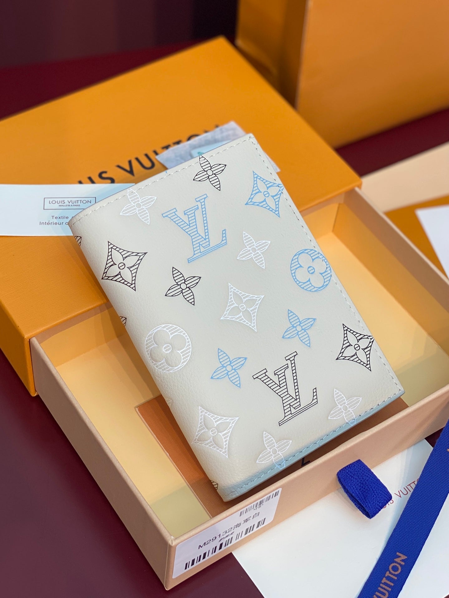 White bi-fold wallet with blue monogram pattern on exterior.