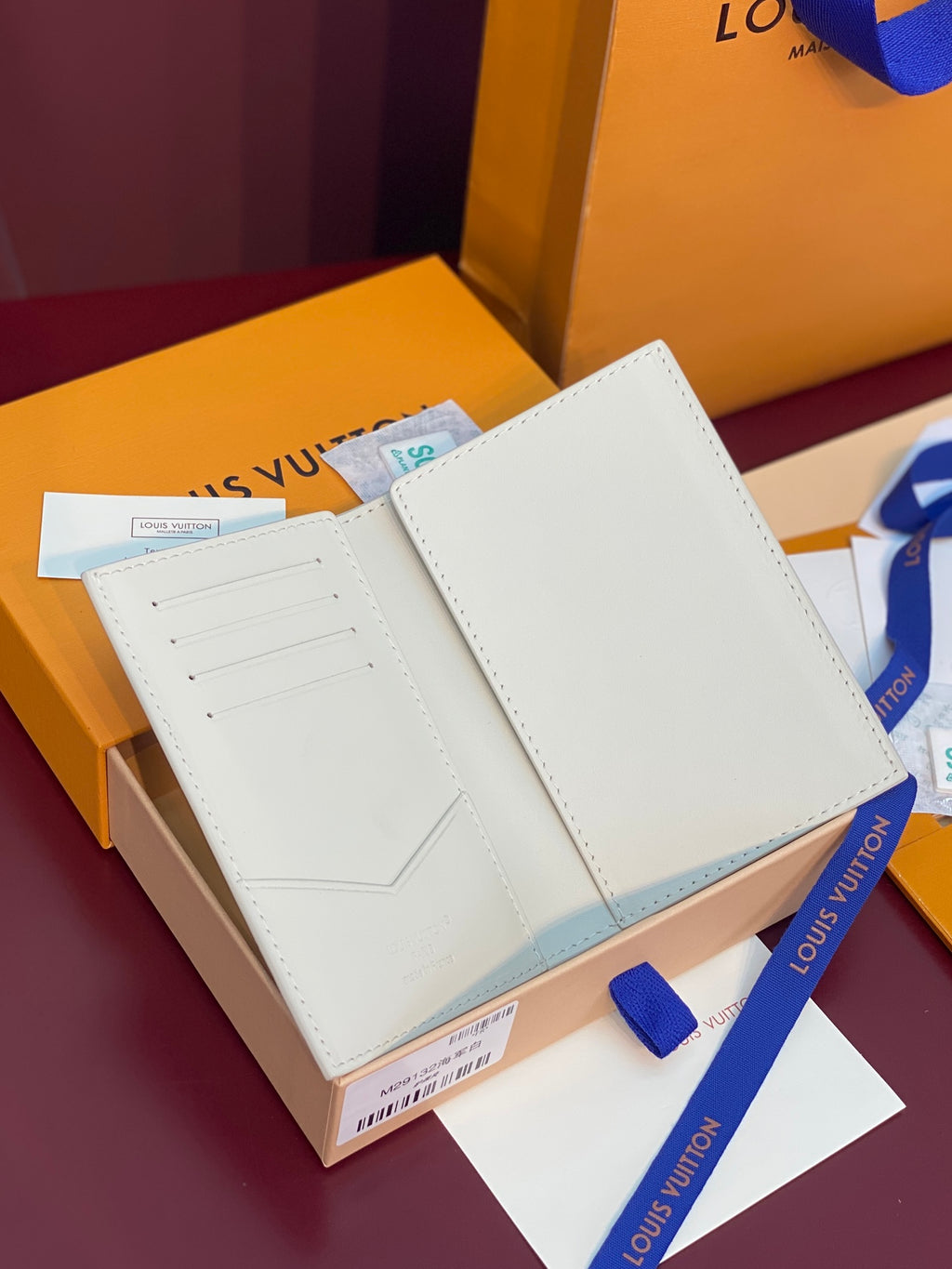 White bi-fold wallet open, showing card slots and smooth interior panels.