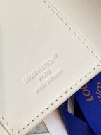 White leather card case with embossed Louis Vuitton text and stitched edge seam