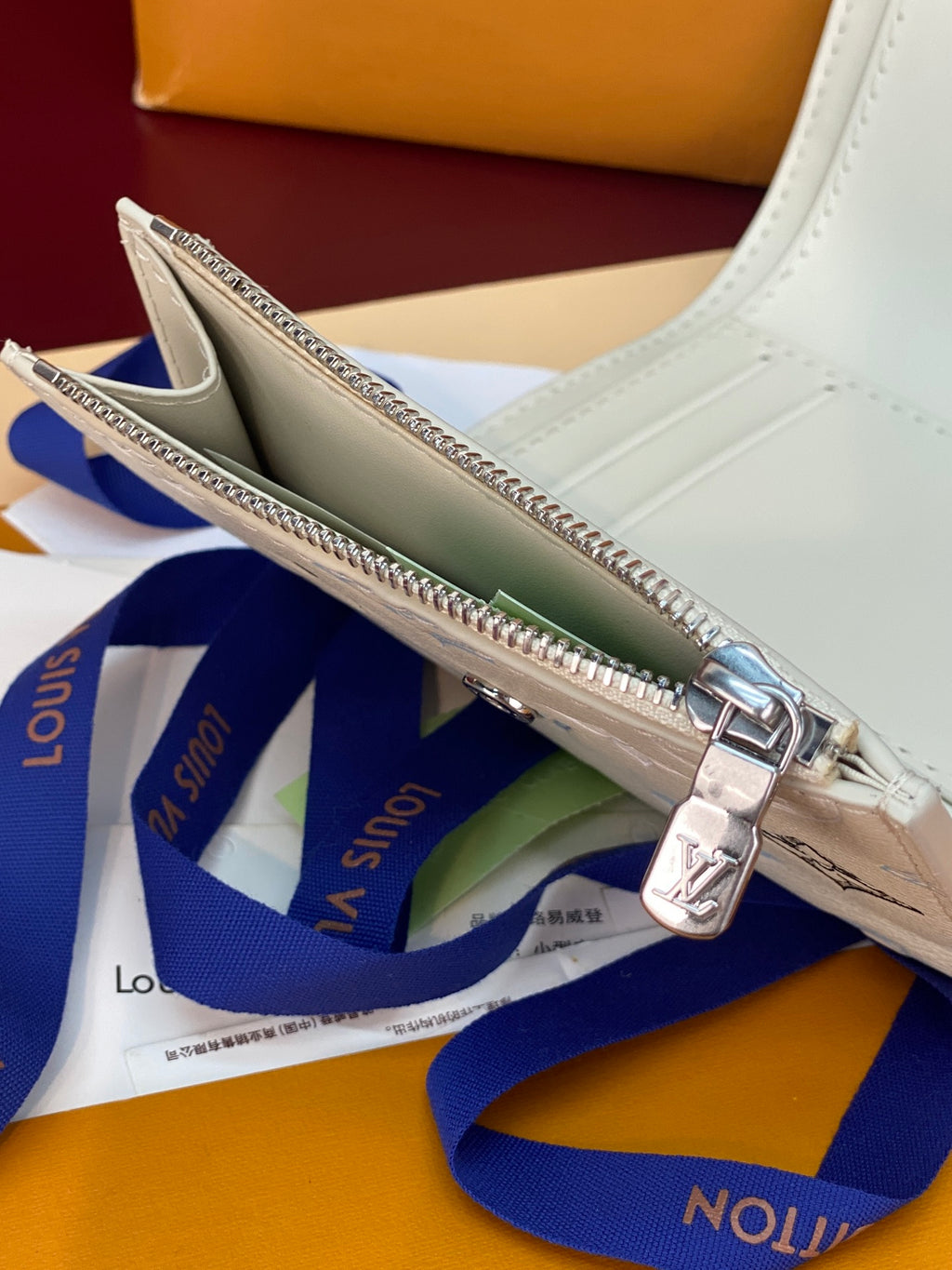 Louis Vuitton zip card case interior view, white leather with card slots and zipper