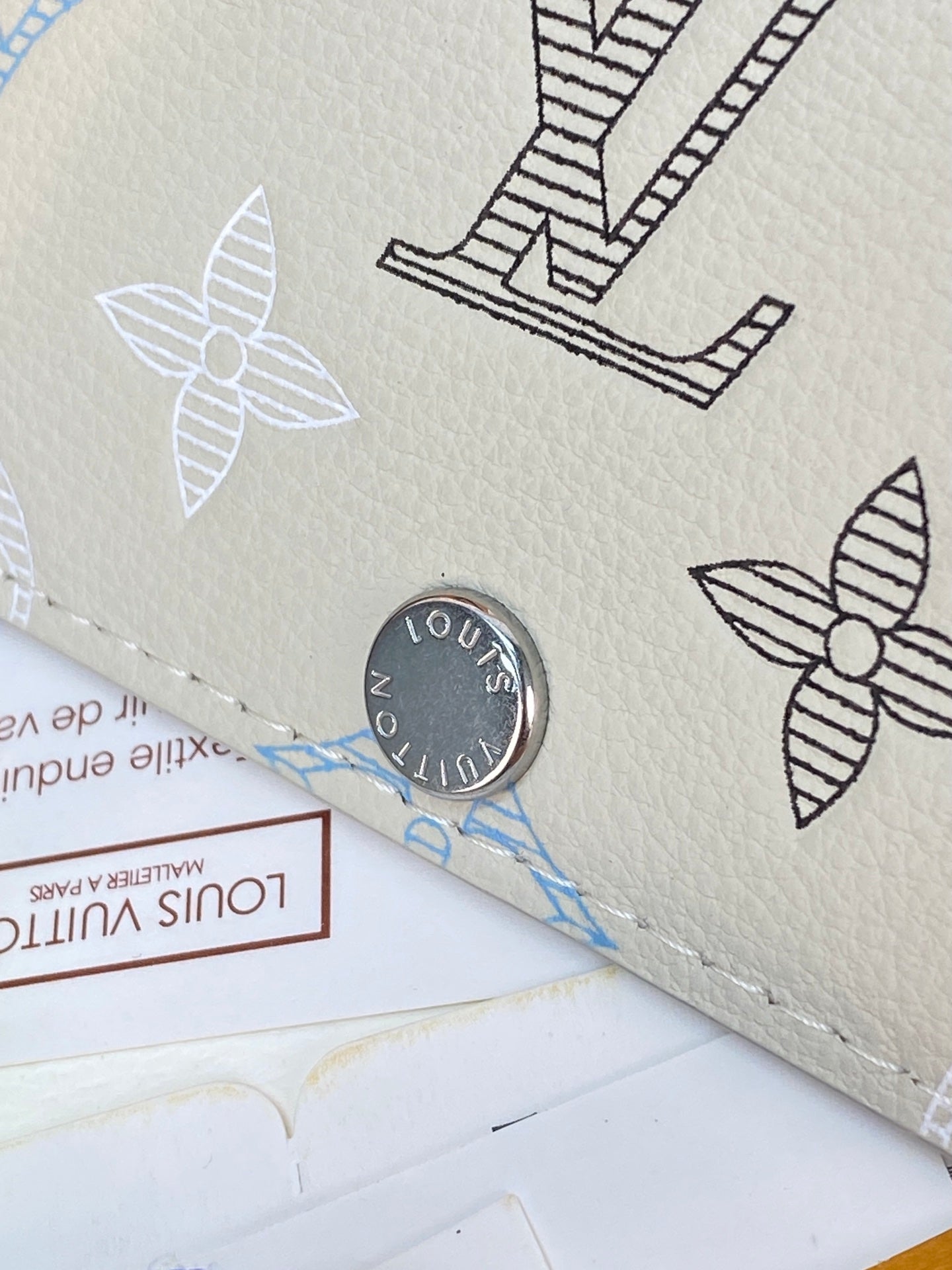 Louis Vuitton card case close-up, light white leather with monogram icons and logo