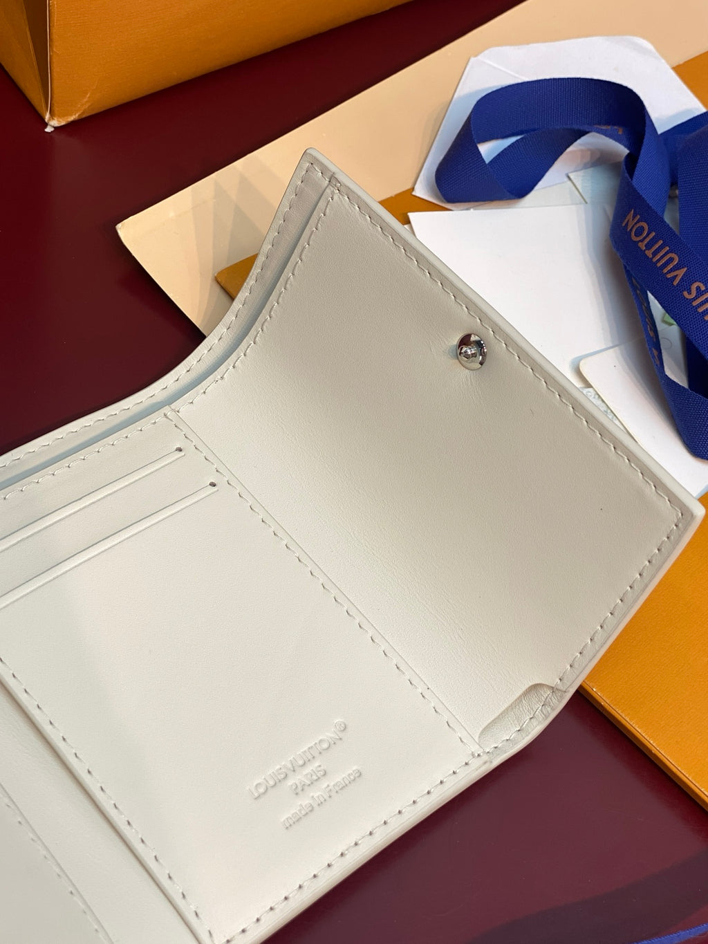 White small wallet front view with snap panel and stitched edges, interior visible