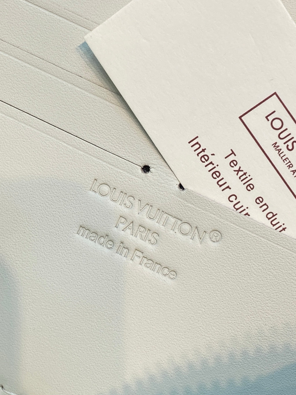 Small wallet care label inside with text and Louis Vuitton marking on tag.