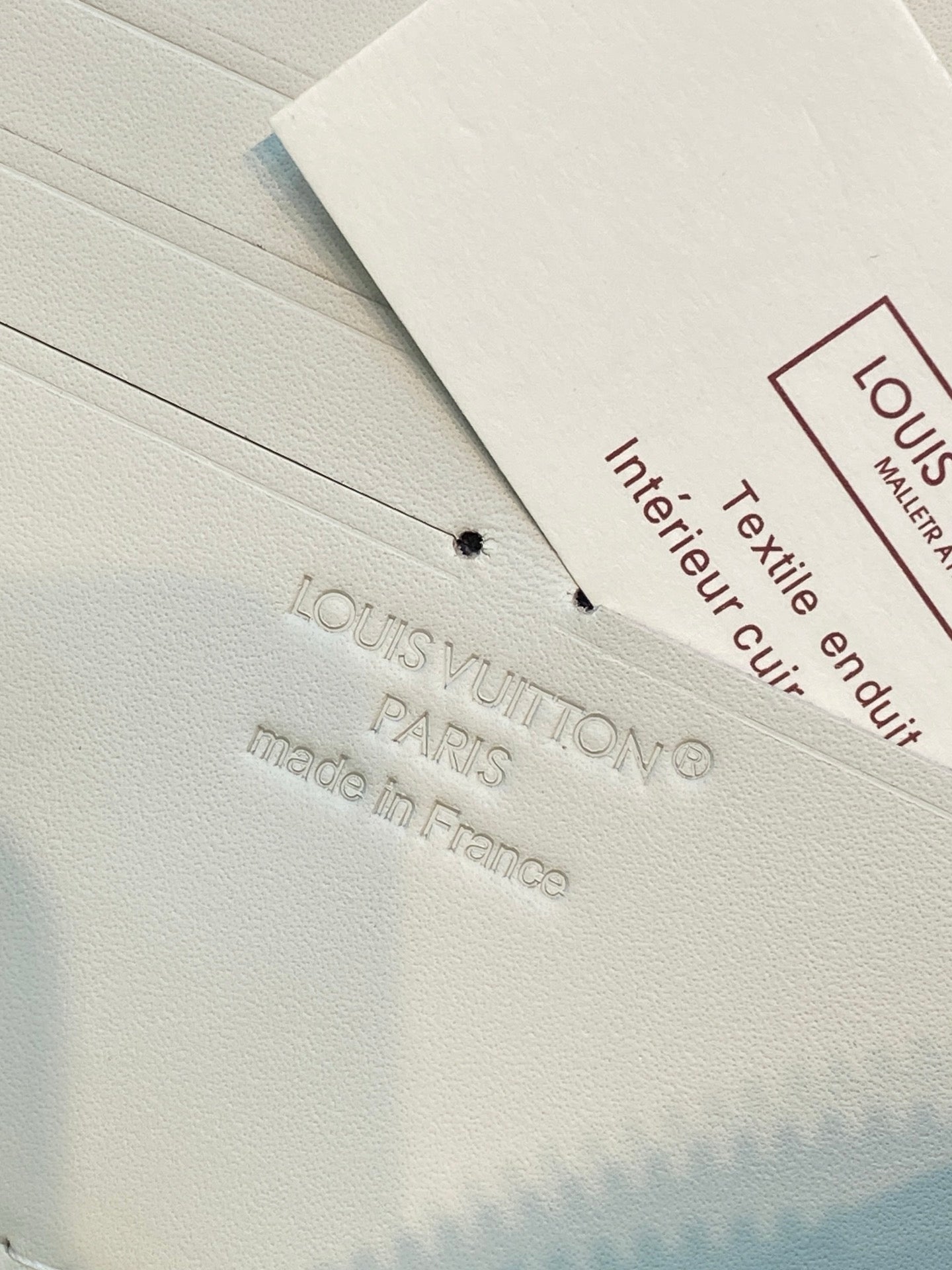 Louis Vuitton care tag on white fabric with printed text and logo