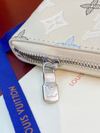 Small zip wallet corner close-up with silver zipper pull and Louis Vuitton charm.
