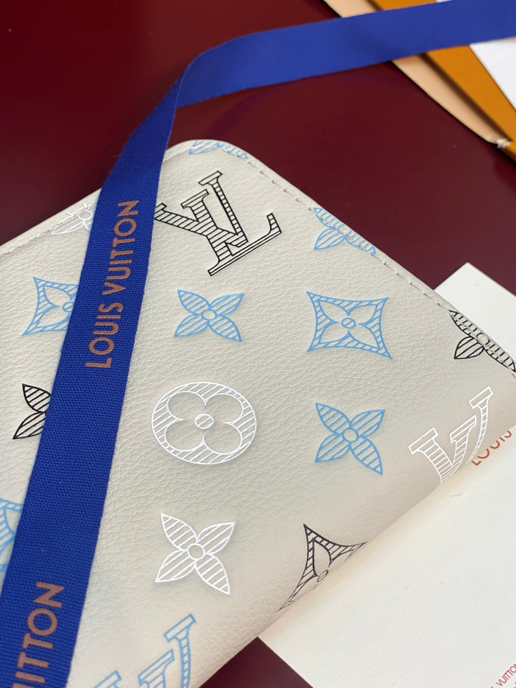 Louis Vuitton zip wallet exterior close-up with blue symbols on white leather