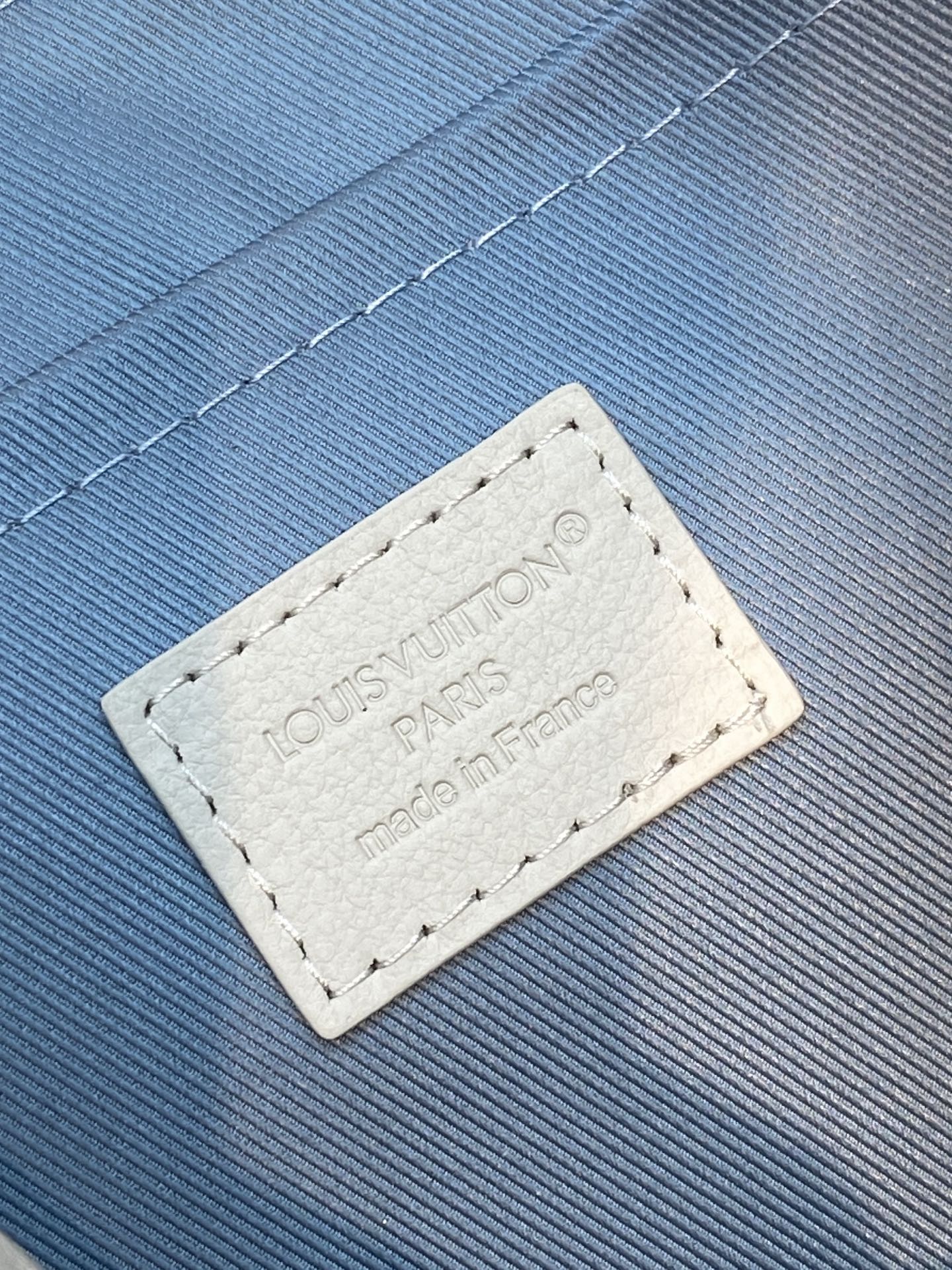 Beige leather label with manufacturer text on textured blue strap