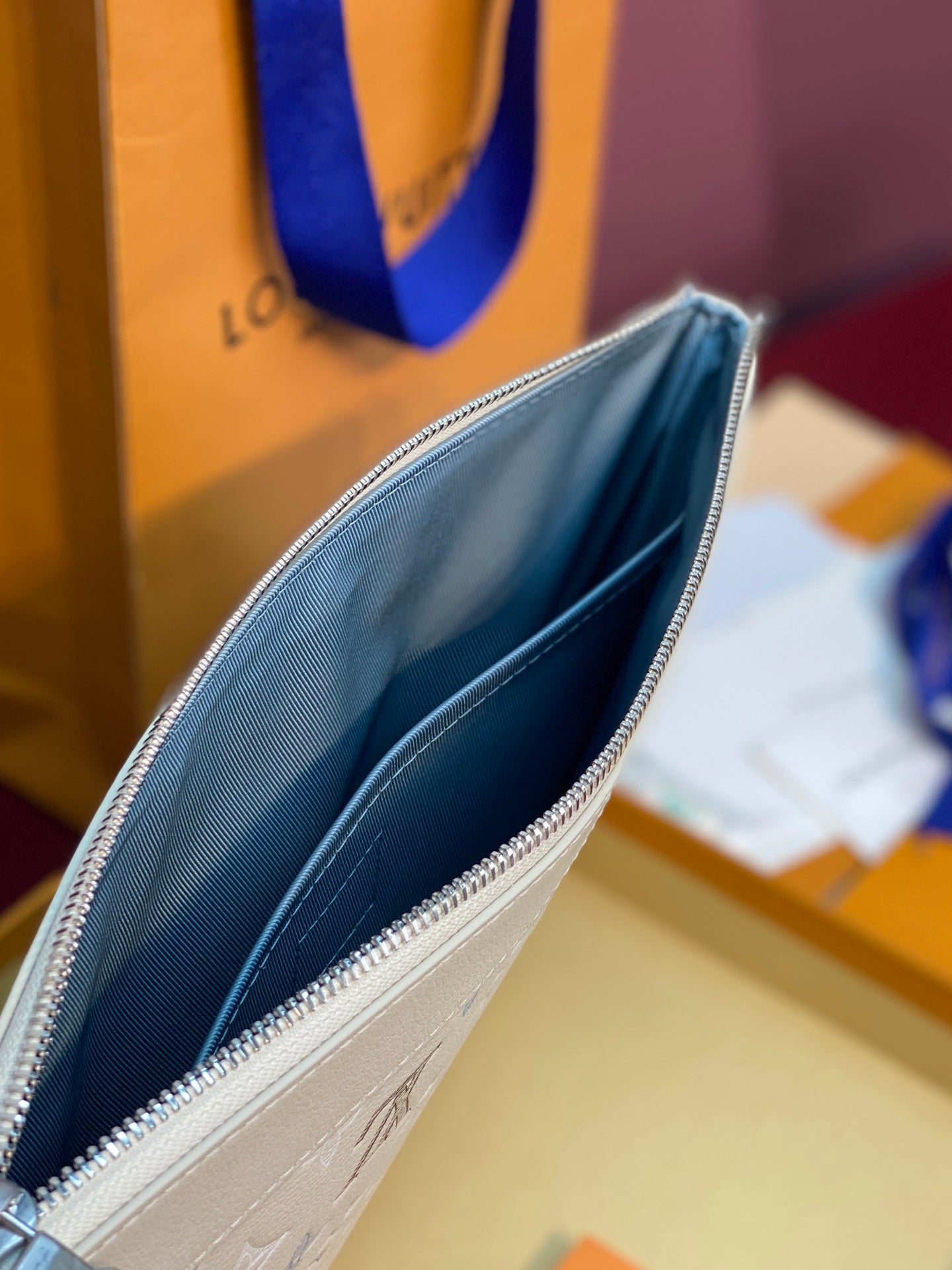 Light beige monogram zip pouch with blue interior lining and zipper edge