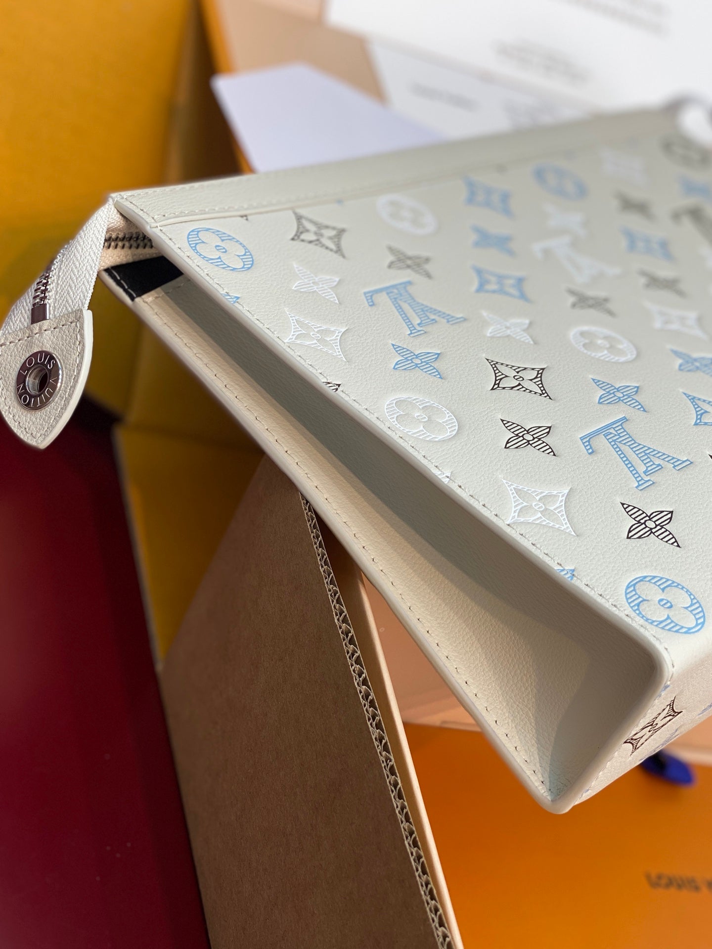 Louis Vuitton monogram clutch bag with leather strap tab and cream blue pattern