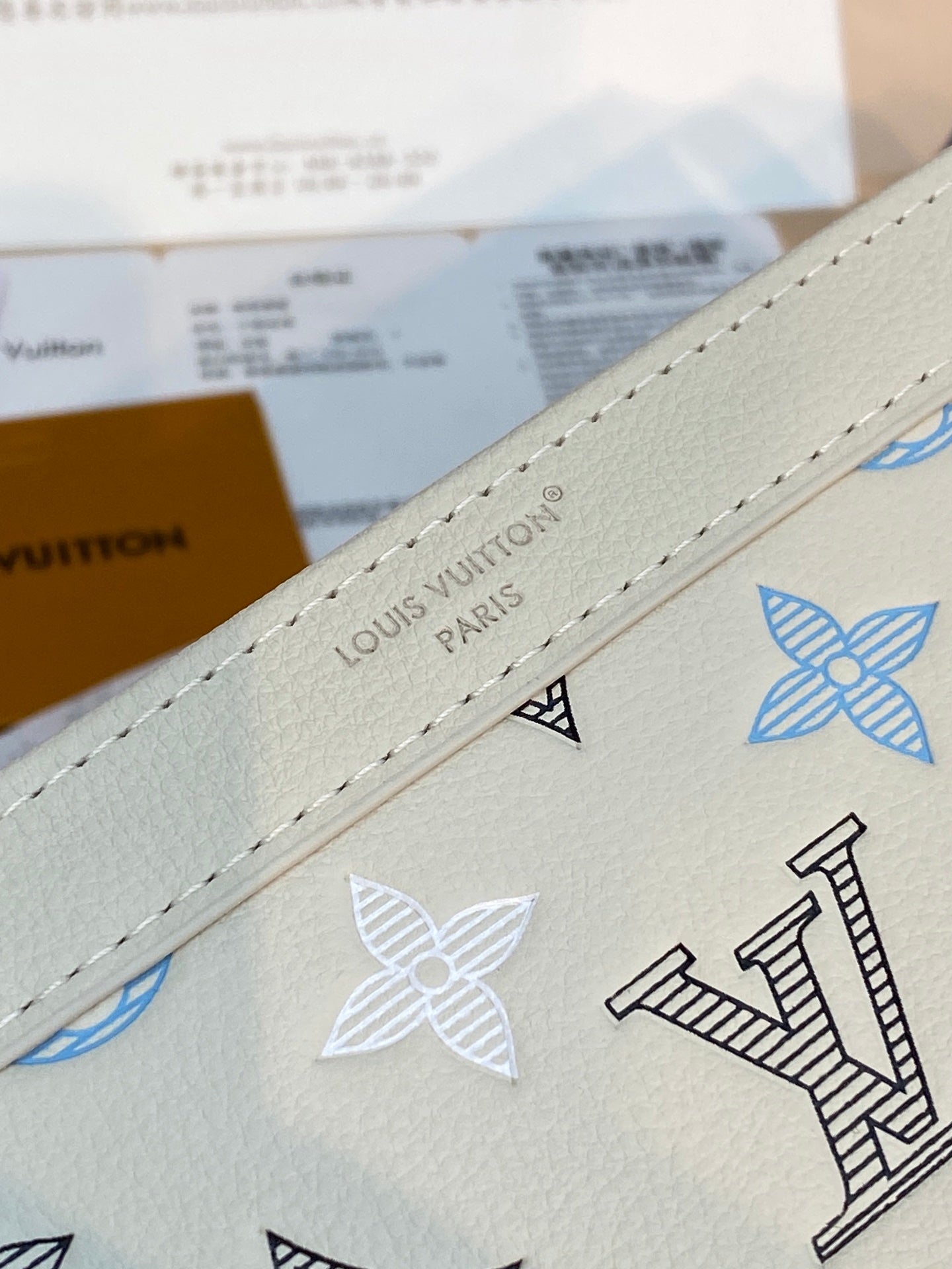 Light gray Louis Vuitton bag strap edge with stitched trim and blue monogram motifs
