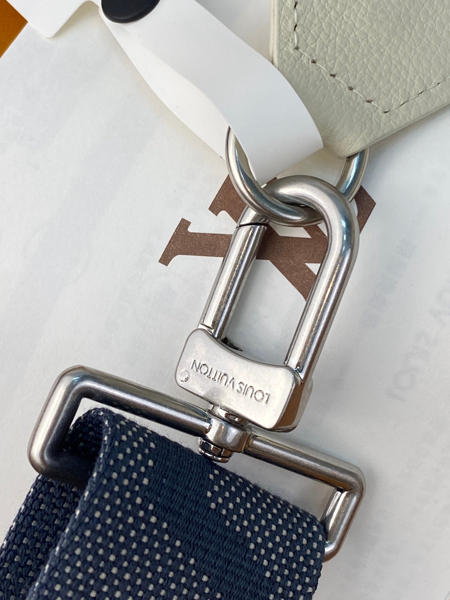 Louis Vuitton small bag metal hardware close-up with navy textured strap and clasp