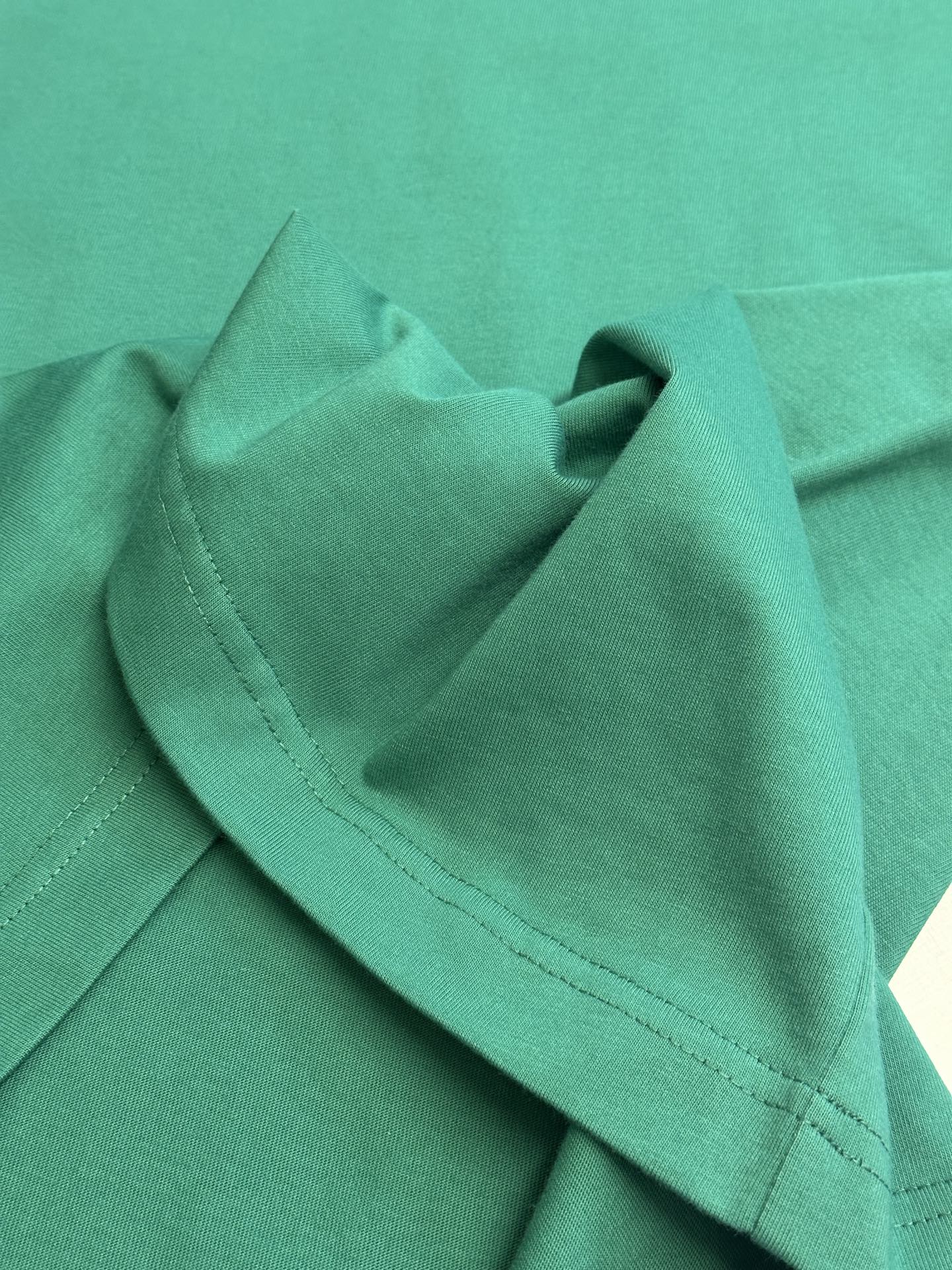 Green short-sleeve T-shirt showing shoulder seam and stitched edge