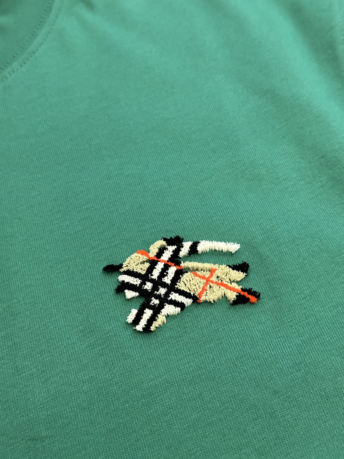 Green short-sleeve T-shirt with colorful embroidered crest emblem