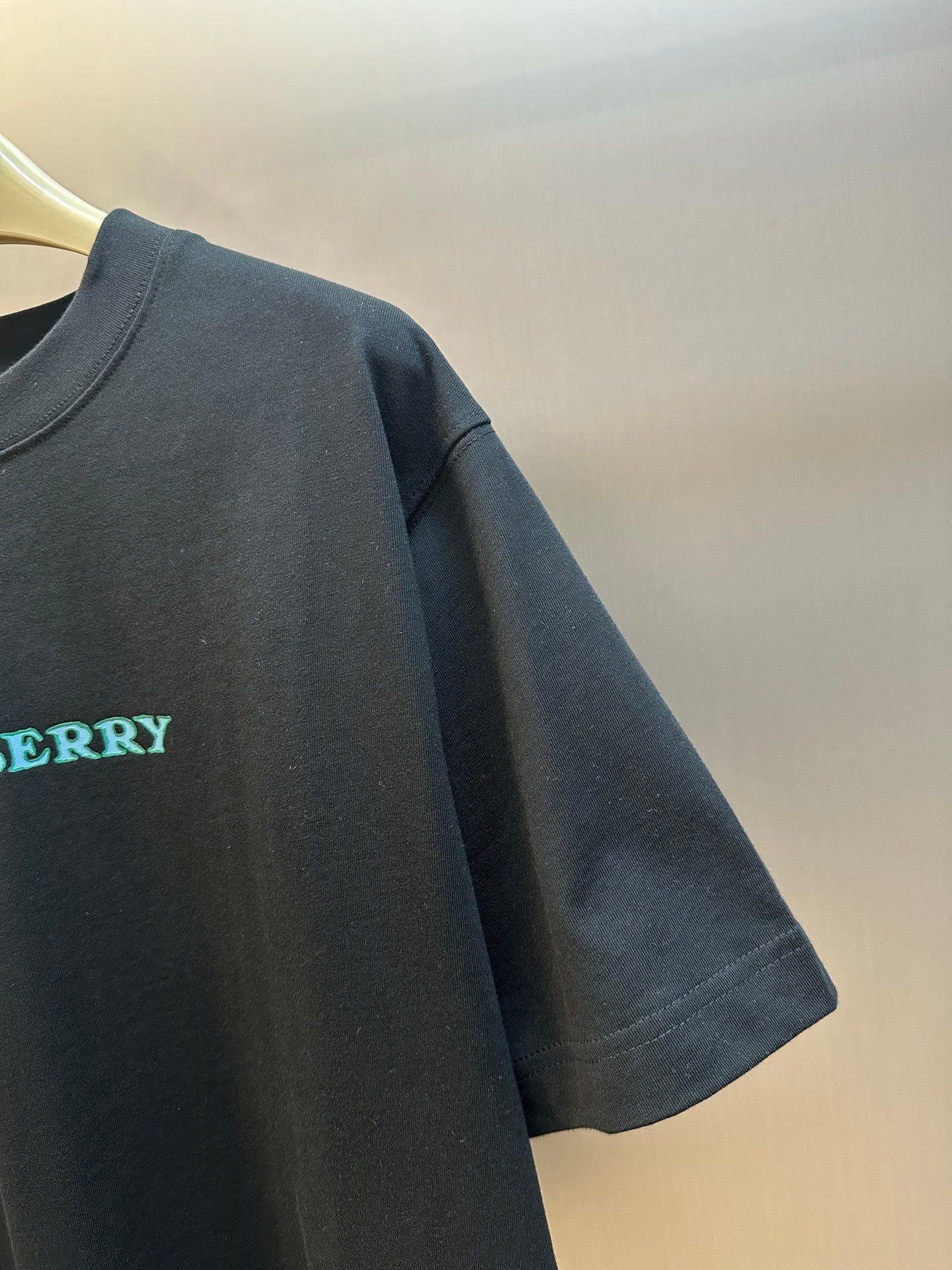 Black T-shirt sleeve with embroidered Burberry logo in teal