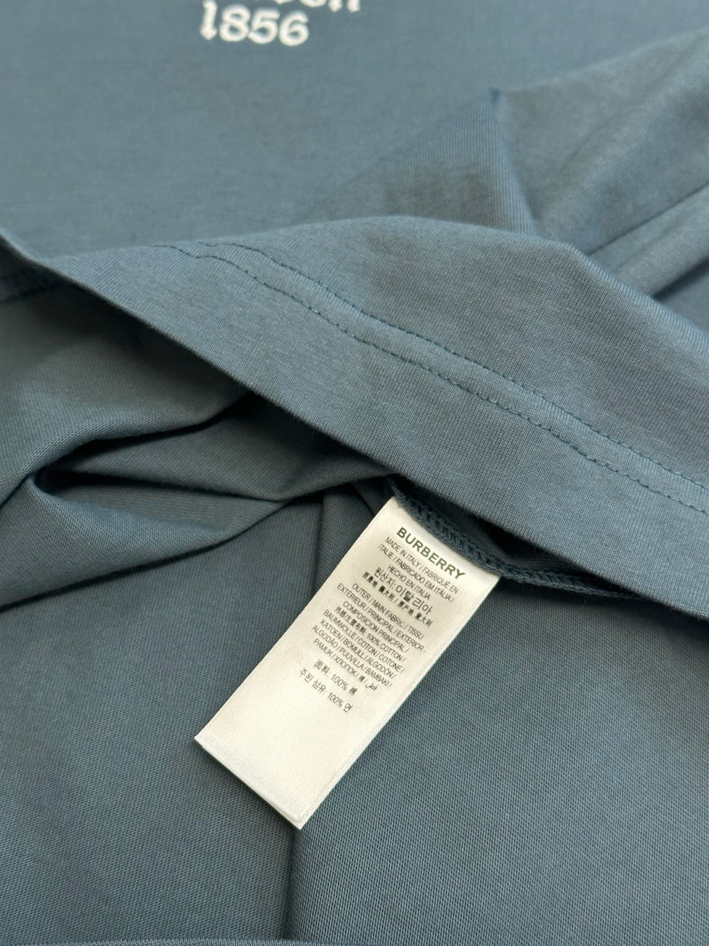Blue T-shirt fabric with side seam and white product label under collar area