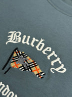 Close-up of embroidered Burberry logo graphic on blue short-sleeve T-shirt