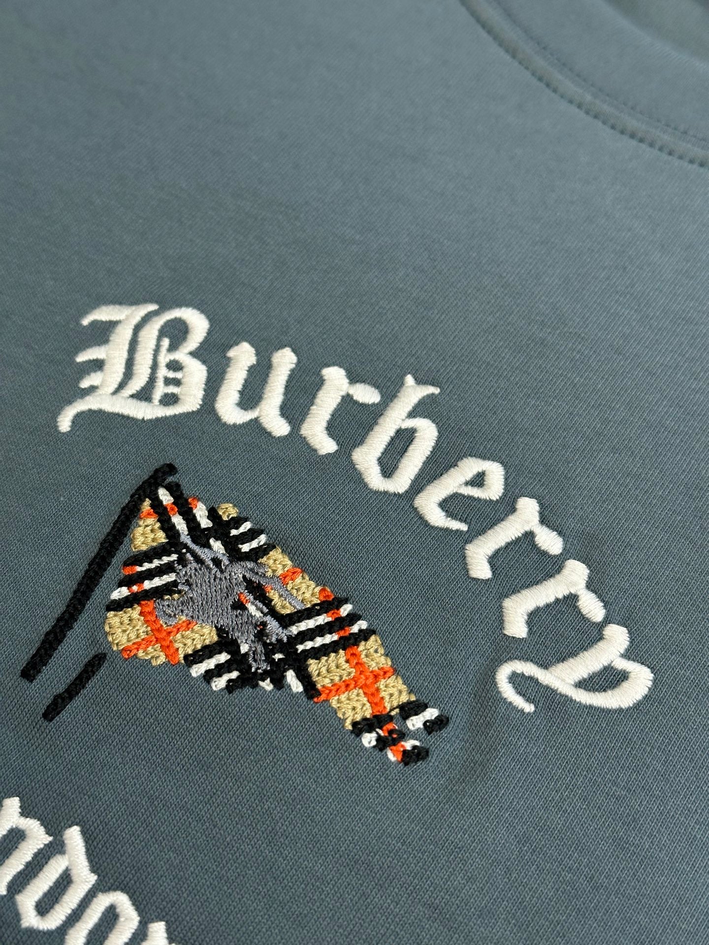 Close-up of embroidered Burberry logo graphic on blue short-sleeve T-shirt