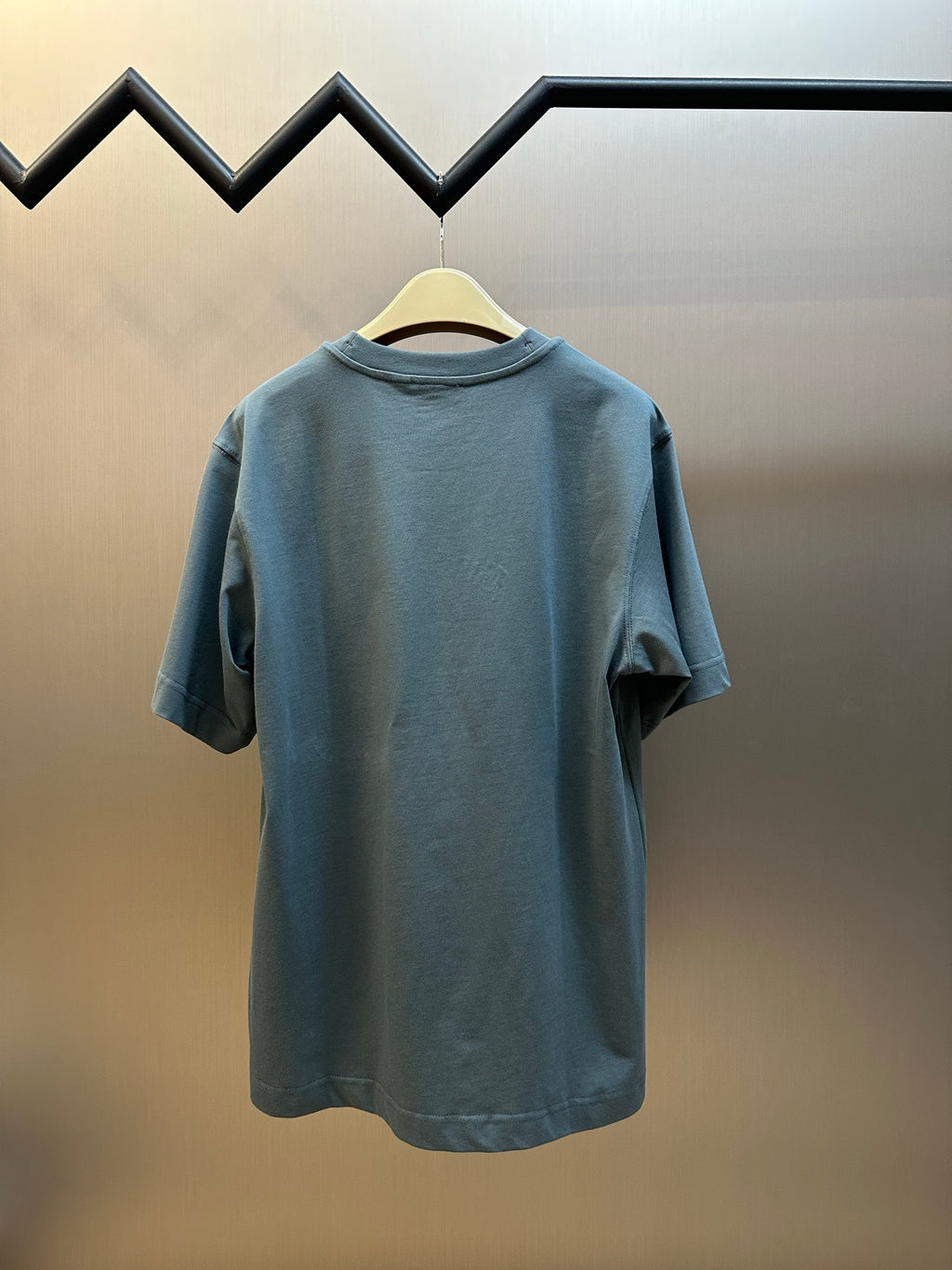 Blue short-sleeve T-shirt with crew neck, plain back view on hanger