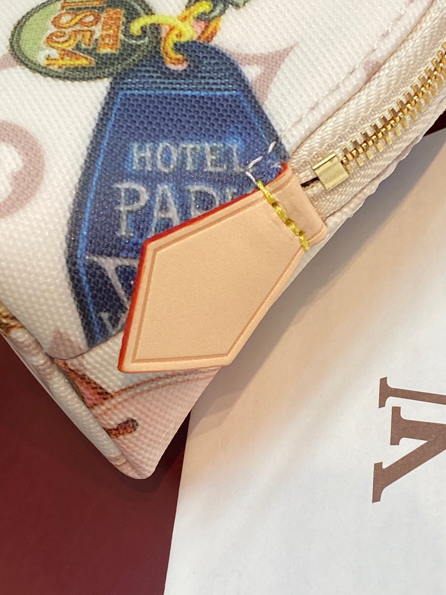 Louis Vuitton pouch close-up with gold zipper pull and “HOTEL PAD” patch