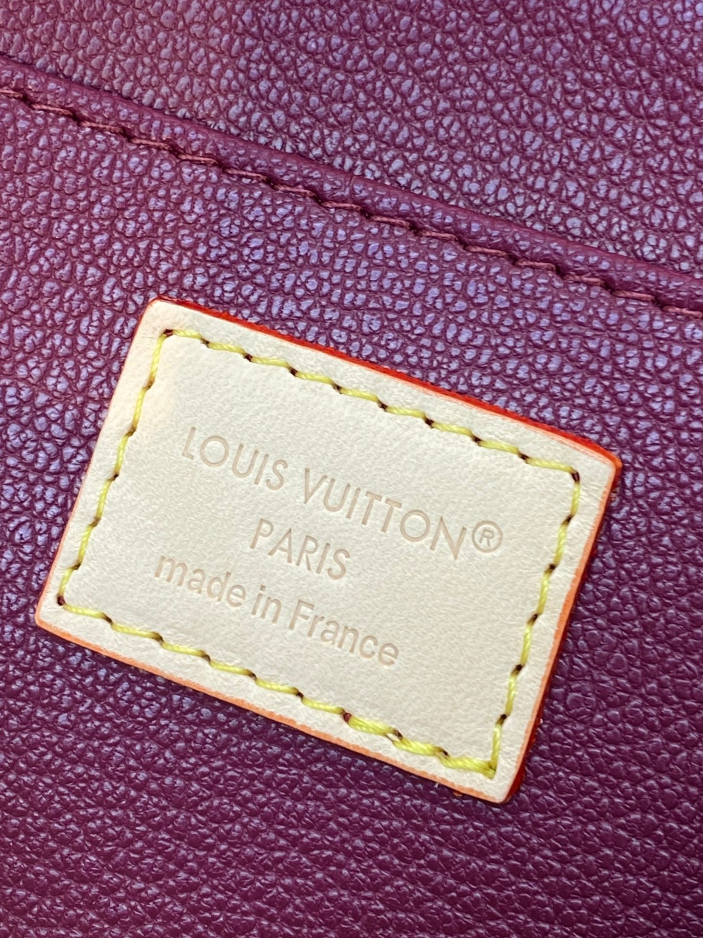 Louis Vuitton leather label with “Louis Vuitton Paris” stitched on purple pouch