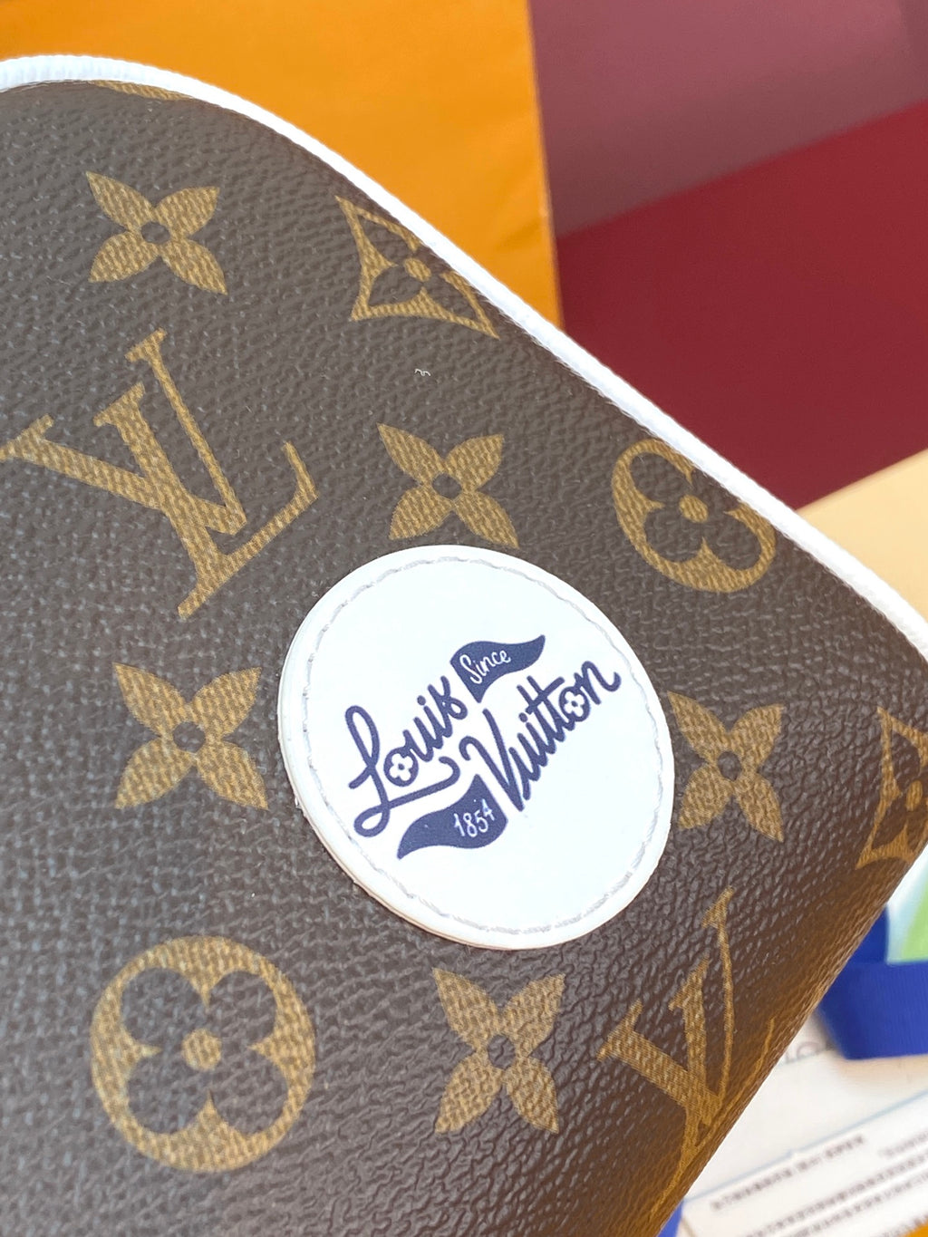 Louis Vuitton monogram canvas with circular logo badge and white edge trim