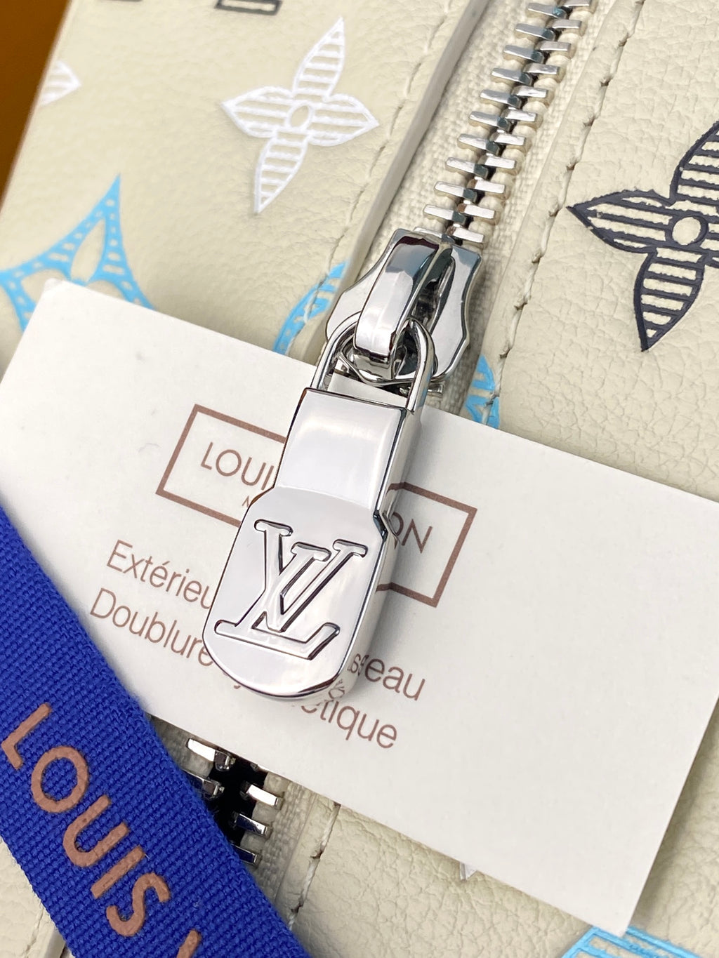 Louis Vuitton lock hardware with care card reading 'Extérieur Cuir de veau' on beige
