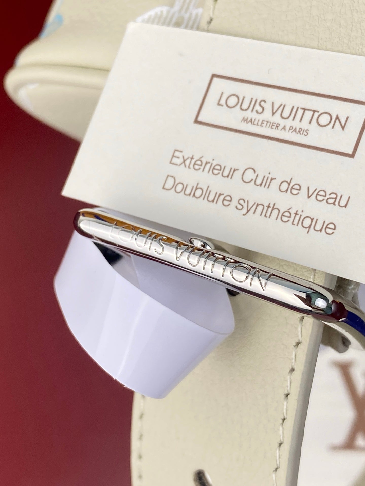 Louis Vuitton care tag and metal hardware on light beige leather strap