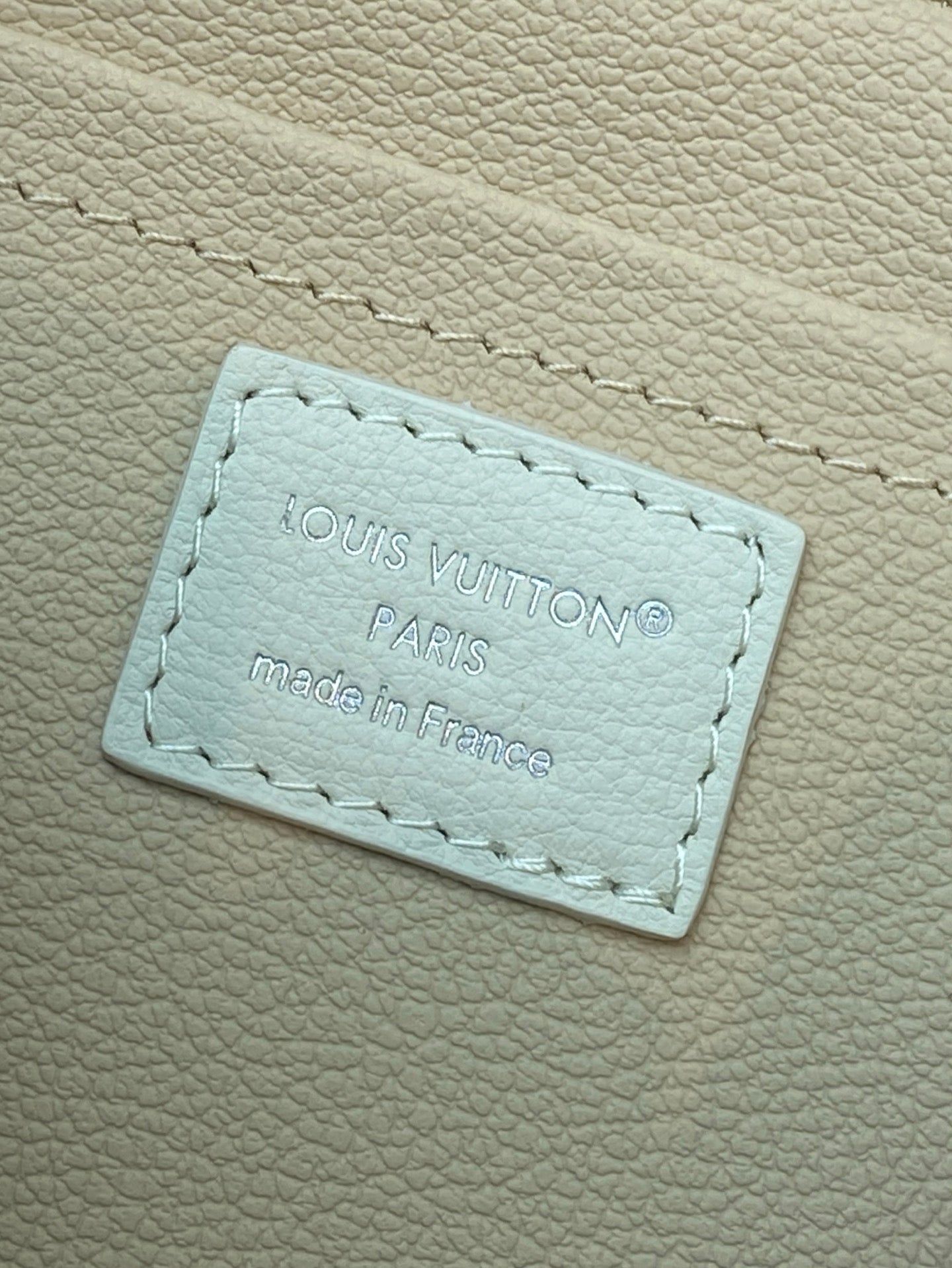 Louis Vuitton interior leather label patch with 'Paris' text on light beige