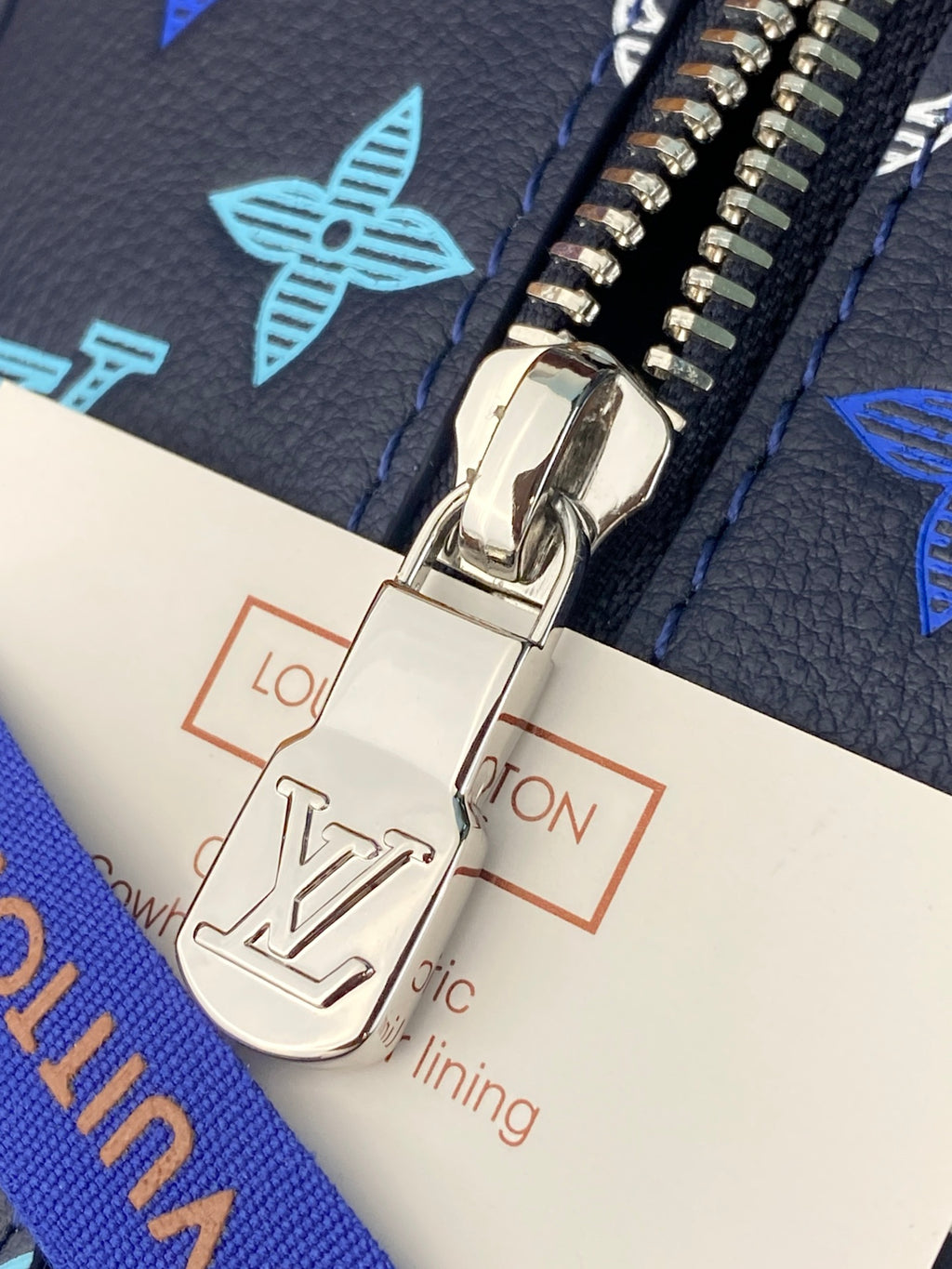 Louis Vuitton zipper pull and hardware detail over branded fabric lining tag