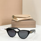 Black cat-eye glasses with dark lenses and gold-tone hinge logo on the temples