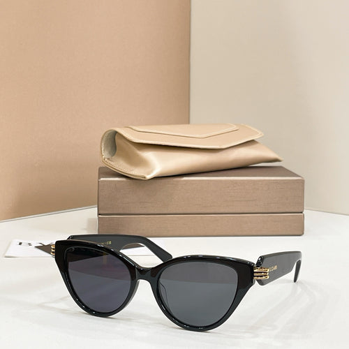 Black cat-eye glasses with dark lenses and gold-tone hinge logo on the temples