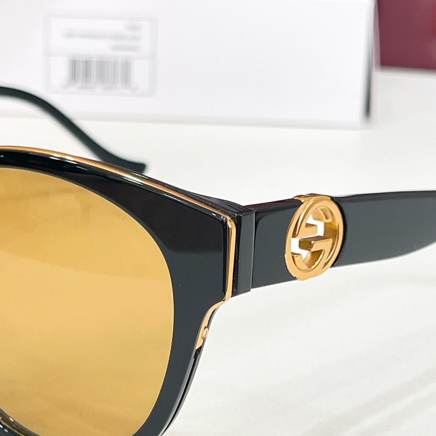 Gucci sunglasses close-up: gold-tone double G emblem on black temple