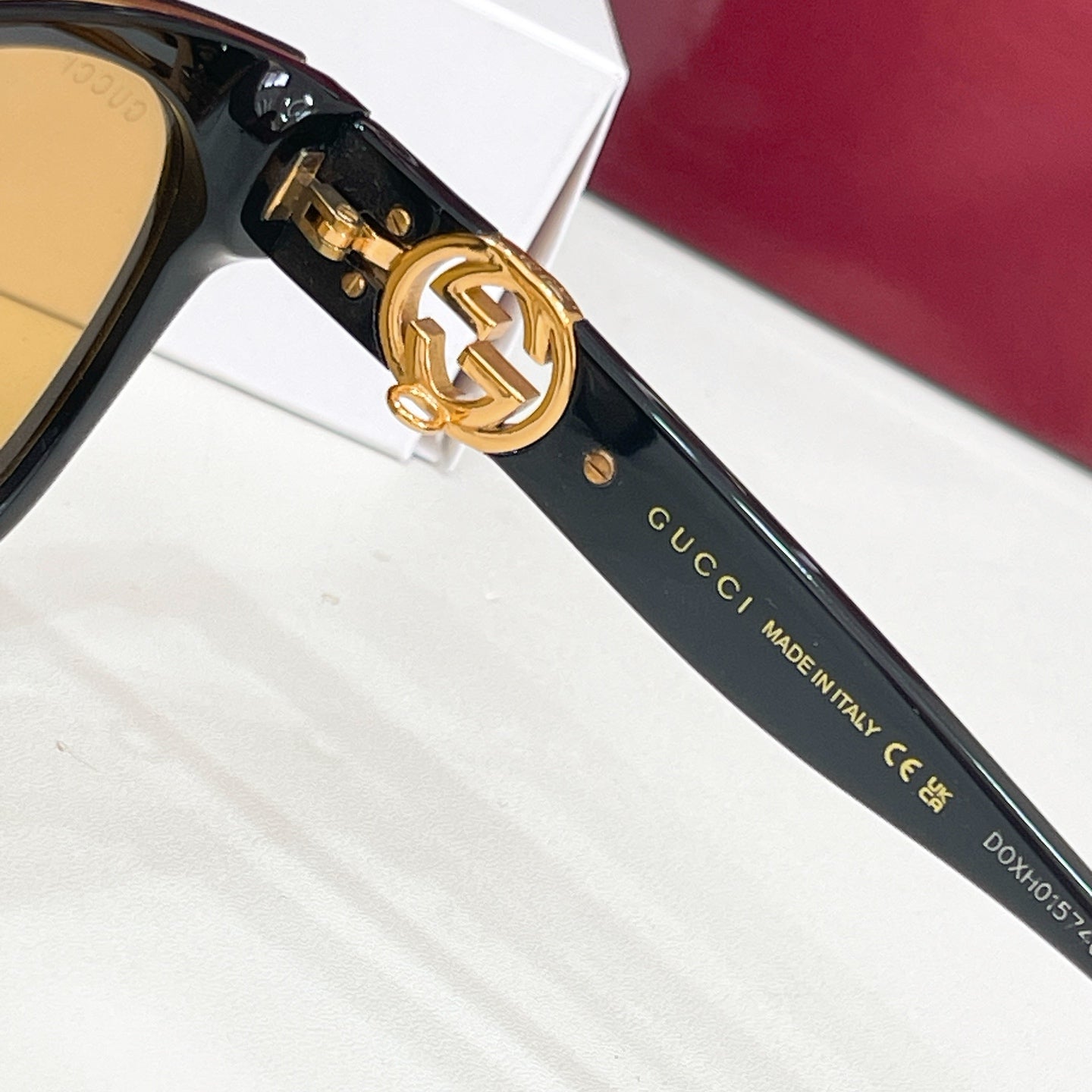Gucci sunglasses close-up: black temple with gold logo and Made in Italy text