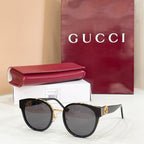Gucci sunglasses with black frames and dark gray lenses, gold-tone logo on bridge