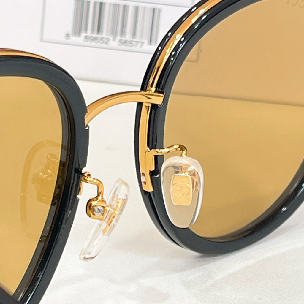 Gucci sunglasses close-up: gold hinge and clear rivet on black frame