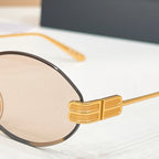 Gold sunglasses hinge detail with dark lens edge and thin metal frame
